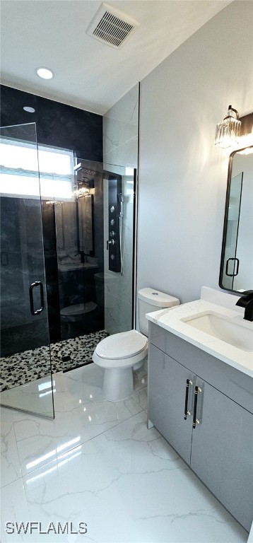 bathroom featuring a shower with door, vanity, and toilet