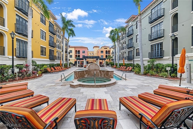 view of property's community with a hot tub and a patio