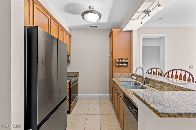 kitchen featuring appliances with stainless steel finishes, sink, kitchen peninsula, light stone countertops, and a breakfast bar area