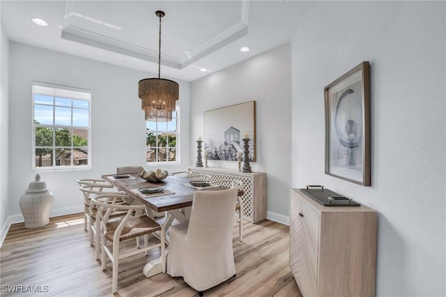 dining room featuring a chandelier, light hardwood / wood-style floors, and a tray ceiling