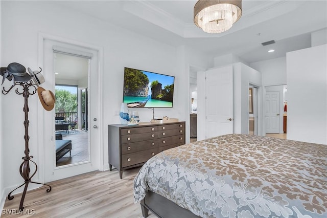 bedroom featuring access to exterior, an inviting chandelier, light wood-type flooring, a tray ceiling, and ornamental molding