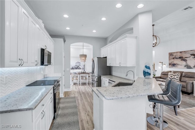 kitchen with kitchen peninsula, white cabinetry, sink, and decorative light fixtures