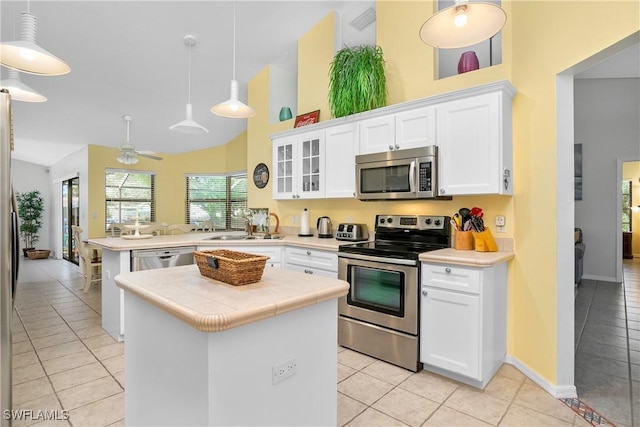 kitchen with kitchen peninsula, white cabinetry, stainless steel appliances, and hanging light fixtures