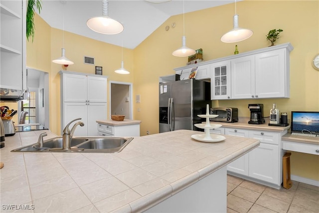 kitchen featuring sink, hanging light fixtures, stainless steel fridge with ice dispenser, high vaulted ceiling, and white cabinets