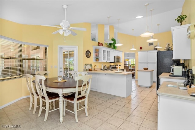 interior space featuring a wealth of natural light, white cabinets, decorative light fixtures, and appliances with stainless steel finishes