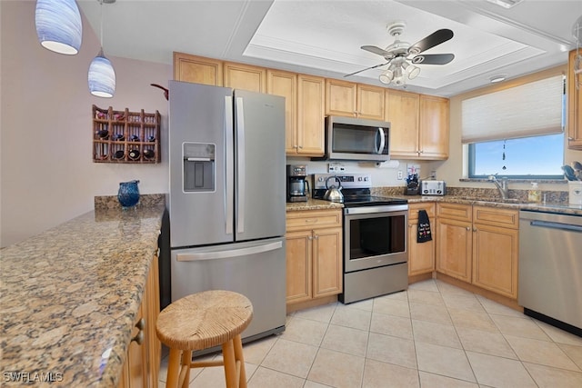 kitchen with stone counters, light tile patterned flooring, appliances with stainless steel finishes, sink, and a raised ceiling