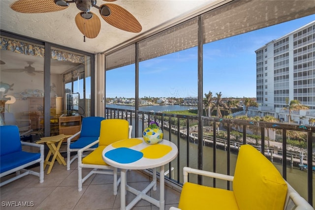 sunroom / solarium with a water view, ceiling fan, and a healthy amount of sunlight