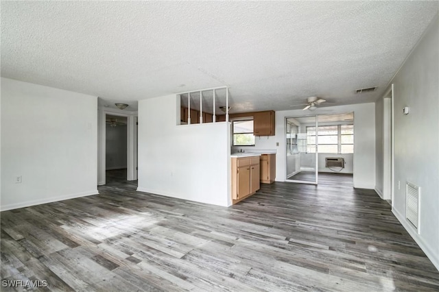 unfurnished living room featuring ceiling fan, dark wood-type flooring, and a textured ceiling