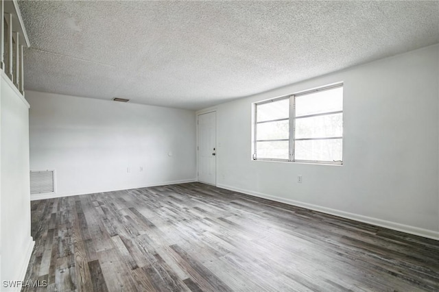 unfurnished room with a textured ceiling and dark wood-type flooring