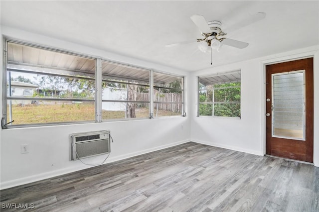 unfurnished sunroom featuring a wall unit AC and ceiling fan