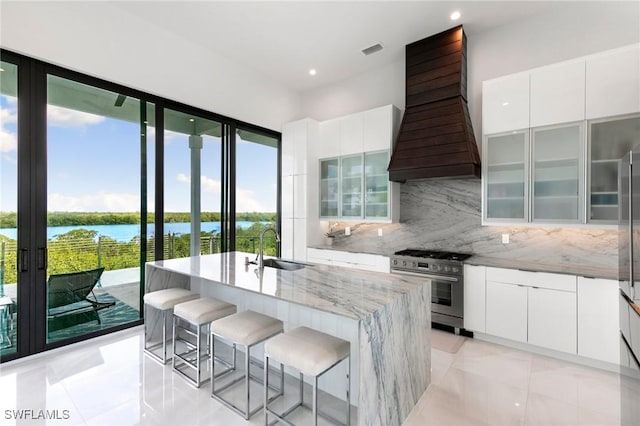 kitchen with a water view, custom exhaust hood, stainless steel range, modern cabinets, and a sink