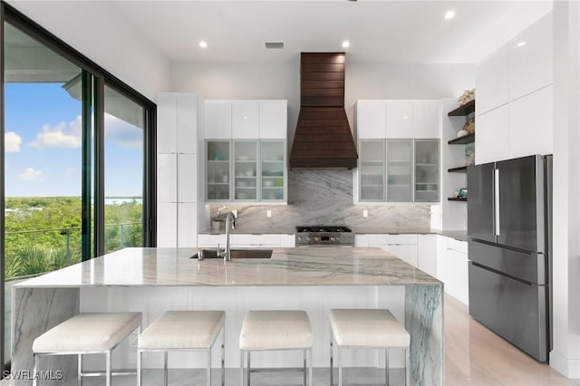 kitchen with custom exhaust hood, stainless steel appliances, modern cabinets, and a sink