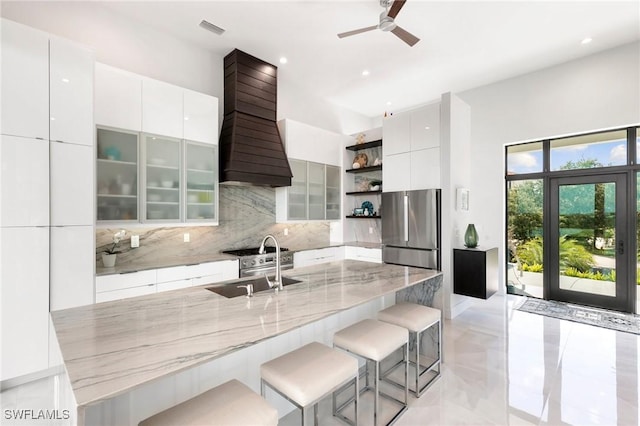 kitchen with modern cabinets, custom range hood, open shelves, backsplash, and freestanding refrigerator