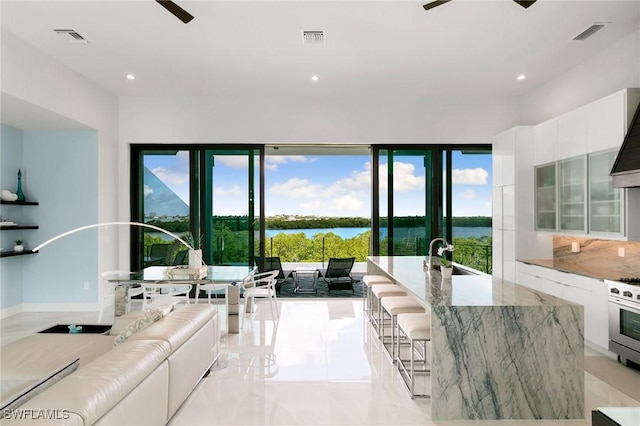 living room featuring visible vents, a ceiling fan, and a water view