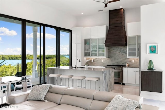 kitchen with a water view, modern cabinets, custom range hood, high end stainless steel range oven, and white cabinets