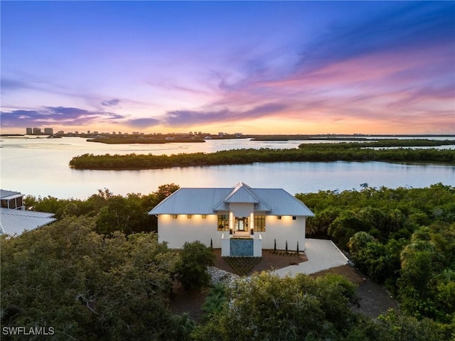 exterior space with metal roof, a water view, and stucco siding