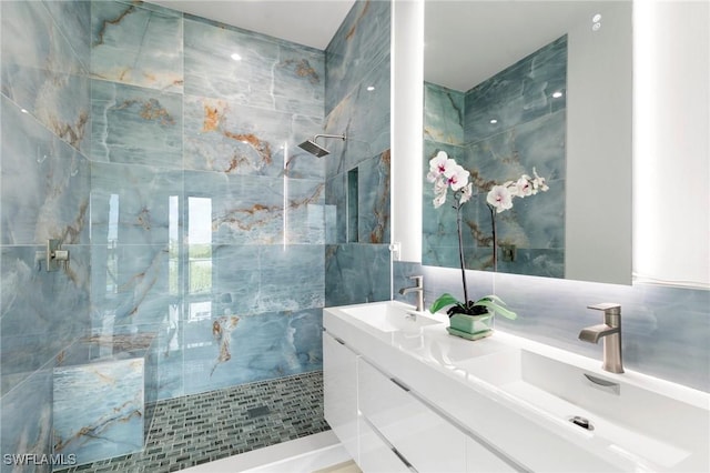 bathroom featuring a sink, tile walls, double vanity, and a tile shower