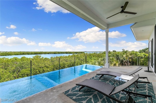 view of pool with outdoor dining space, a patio area, a ceiling fan, and a water view