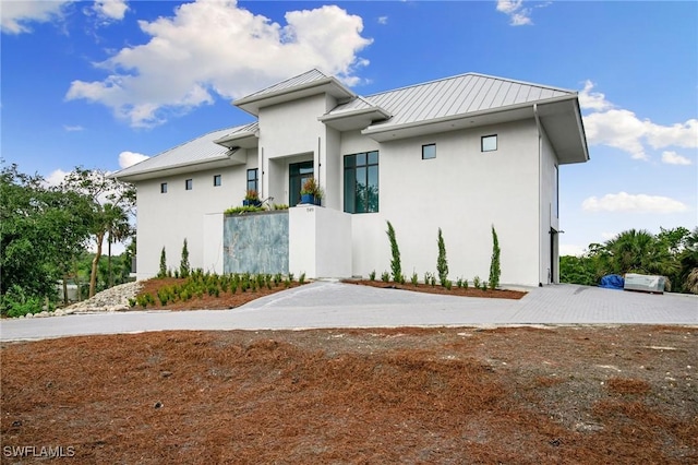 view of front of home with a standing seam roof, metal roof, and stucco siding