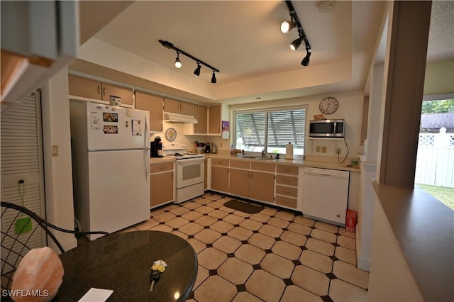 kitchen featuring white appliances, sink, a tray ceiling, and track lighting