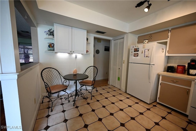 kitchen with white refrigerator and white cabinetry