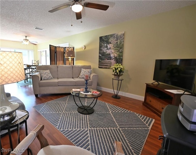 living room with a textured ceiling, ceiling fan, and dark hardwood / wood-style floors