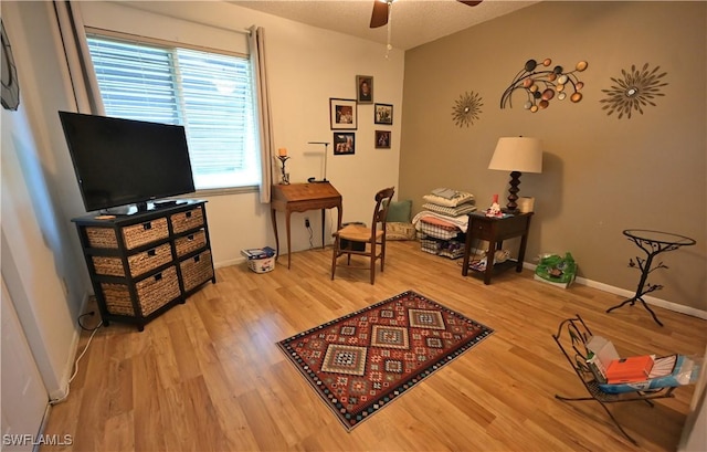 living area featuring ceiling fan, wood-type flooring, and a textured ceiling