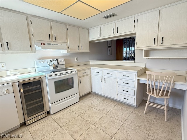 kitchen with light tile patterned flooring, white appliances, and beverage cooler