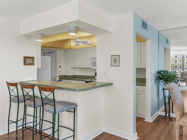 kitchen featuring ceiling fan, dark hardwood / wood-style flooring, white cabinetry, and kitchen peninsula