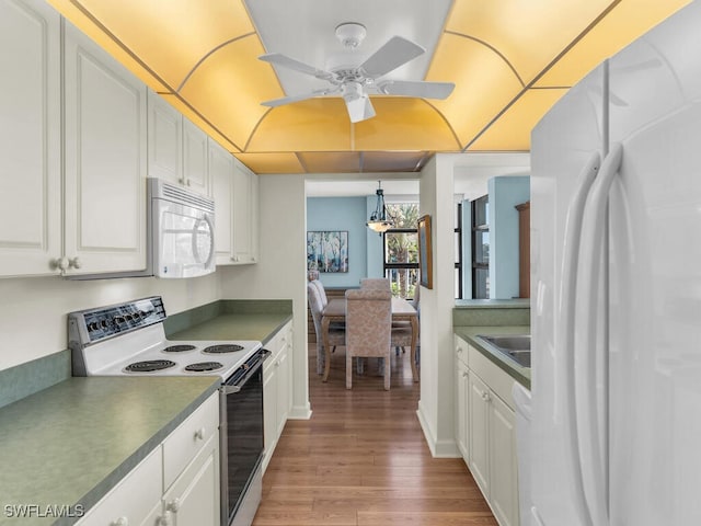 kitchen featuring white cabinets, light wood-type flooring, and white appliances