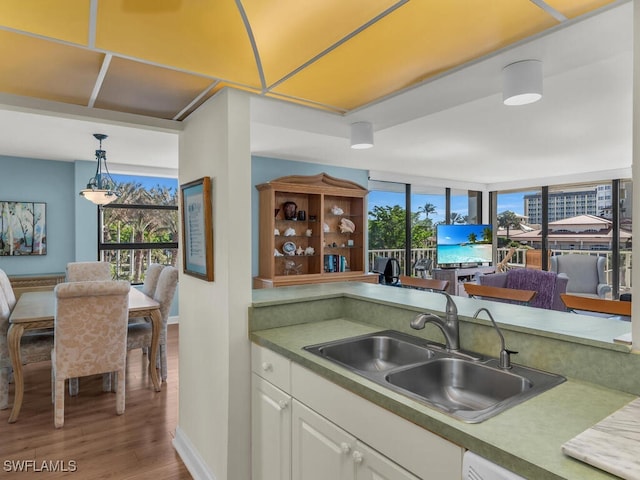 kitchen with hardwood / wood-style floors, dishwasher, white cabinets, sink, and hanging light fixtures