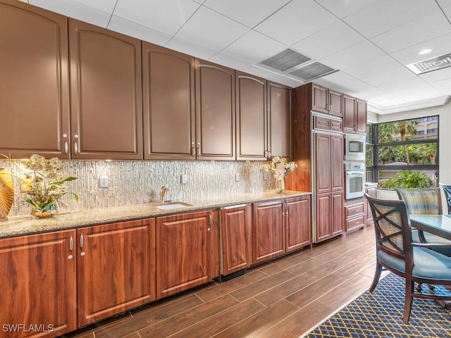 kitchen featuring light stone countertops, dark hardwood / wood-style flooring, stainless steel appliances, and sink