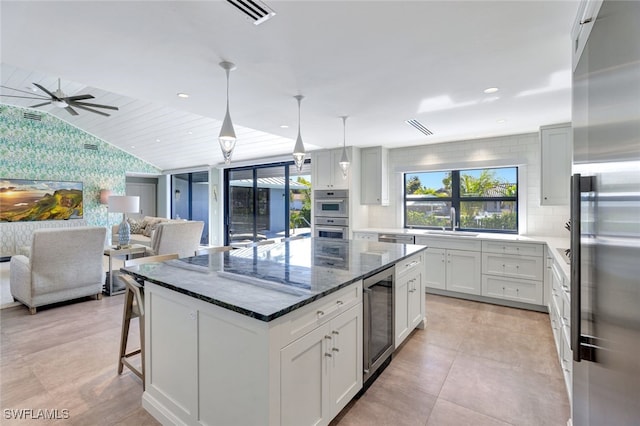 kitchen with white cabinetry, a center island, hanging light fixtures, wine cooler, and appliances with stainless steel finishes