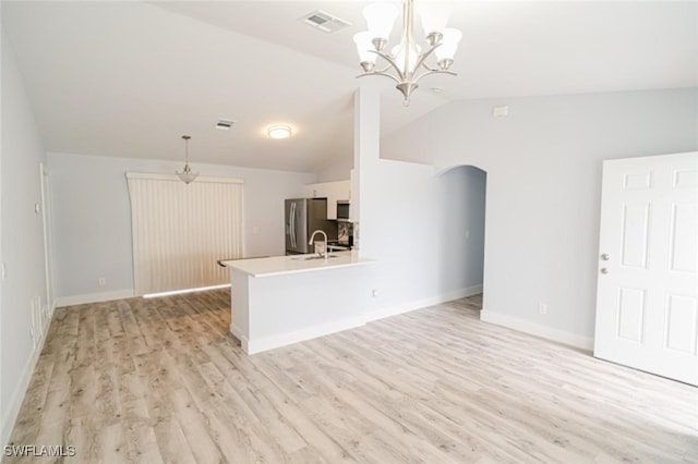 unfurnished living room with light hardwood / wood-style floors, lofted ceiling, sink, and an inviting chandelier