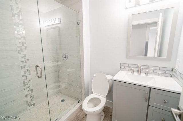 bathroom with hardwood / wood-style floors, vanity, a shower with door, and toilet