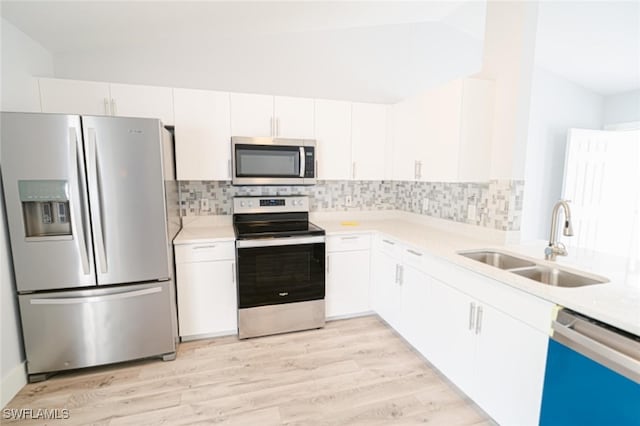 kitchen featuring white cabinets, sink, light hardwood / wood-style flooring, appliances with stainless steel finishes, and tasteful backsplash