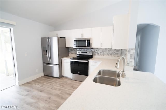 kitchen featuring sink, stainless steel appliances, light hardwood / wood-style floors, lofted ceiling, and white cabinets