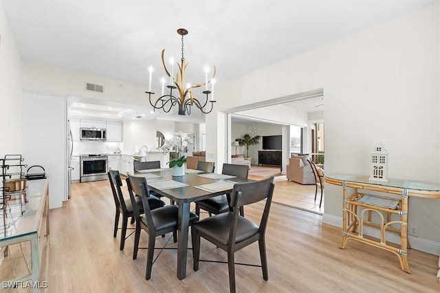 dining area featuring a chandelier, sink, and light hardwood / wood-style floors