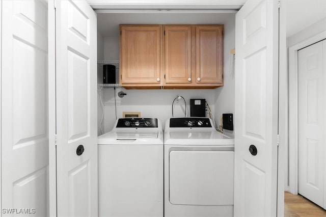 washroom with cabinets, washing machine and dryer, and light hardwood / wood-style flooring