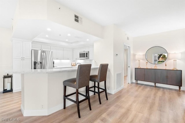 kitchen featuring white cabinets, stainless steel appliances, and light wood-type flooring