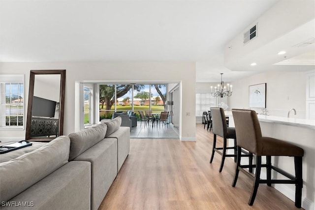 living room with sink, plenty of natural light, a notable chandelier, and light hardwood / wood-style flooring