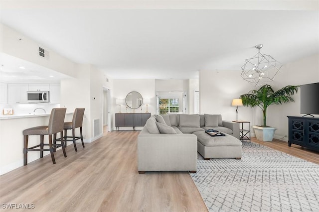 living room featuring light wood-type flooring and a notable chandelier