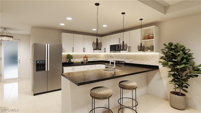 kitchen with pendant lighting, white cabinetry, sink, stainless steel fridge, and a kitchen bar