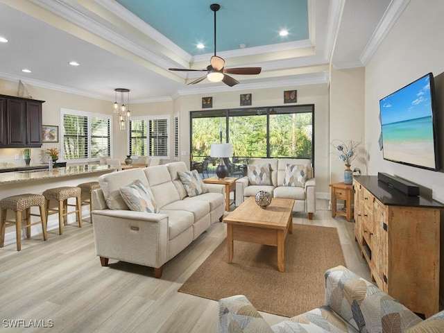 living room with ornamental molding, a tray ceiling, ceiling fan, and light hardwood / wood-style floors