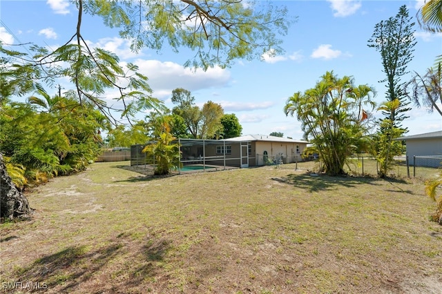 view of yard with a fenced in pool and glass enclosure