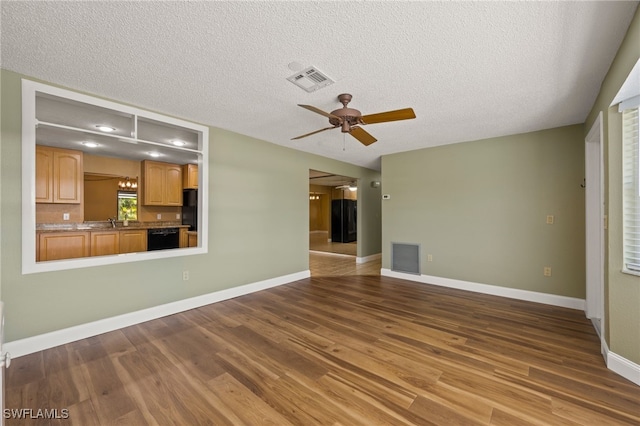 unfurnished living room featuring ceiling fan, sink, a textured ceiling, and hardwood / wood-style flooring