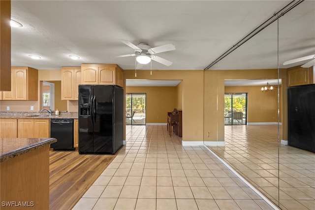 kitchen featuring black appliances, plenty of natural light, light tile patterned floors, and ceiling fan with notable chandelier