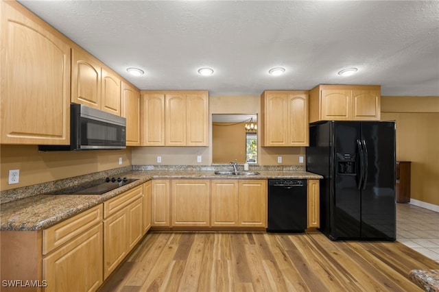 kitchen featuring black appliances, dark stone countertops, sink, and light brown cabinetry