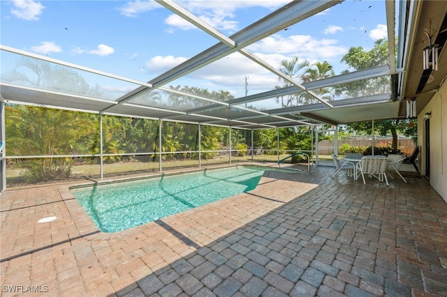 view of pool featuring glass enclosure and a patio