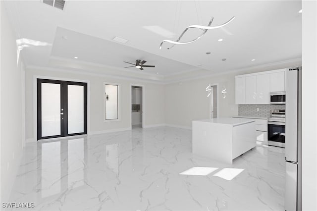 kitchen featuring decorative light fixtures, stainless steel range with electric cooktop, a raised ceiling, and white cabinets